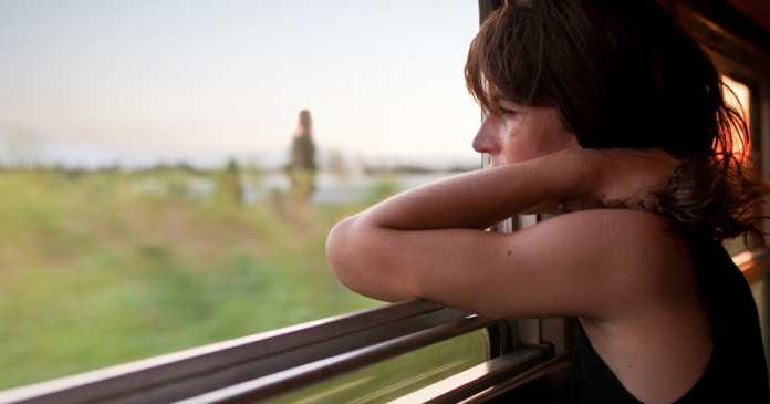 A fellow passenger looking off into the sunset on a train from S