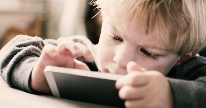 26249508 - little kid playing game on smart phone