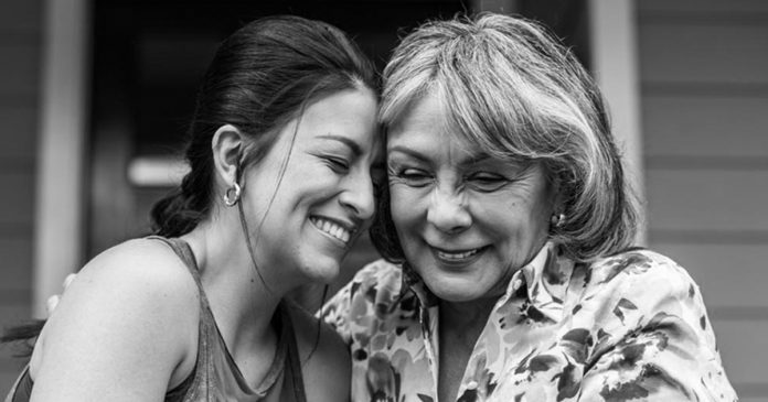 Senior woman and adult daughter laughing on porch