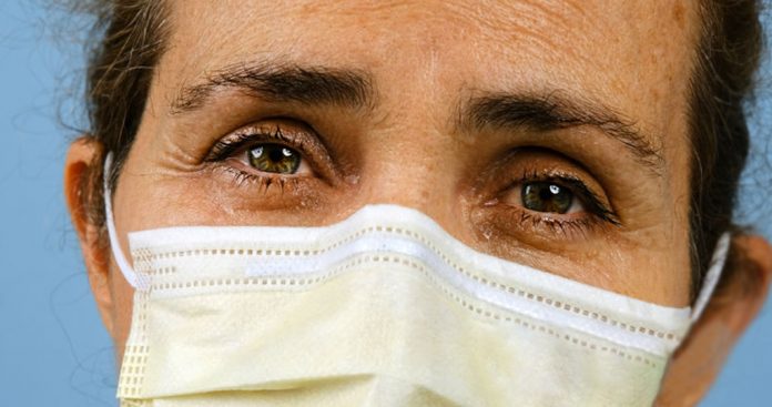 Caucasian Very sad ill mature woman wearing a surgical mask